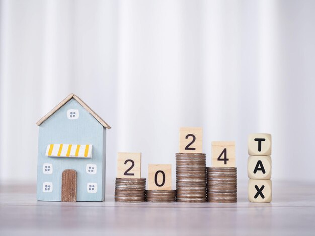 Photo miniature house wooden blocks with the word tax and number 2024 on stack of coins the concept of payment tax for house property investment house mortgage real estate in new year 2024