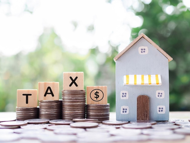 Miniature house Wooden blocks with the word TAX and stack of coins The concept of payment tax for house Property investment House mortgage Real estate