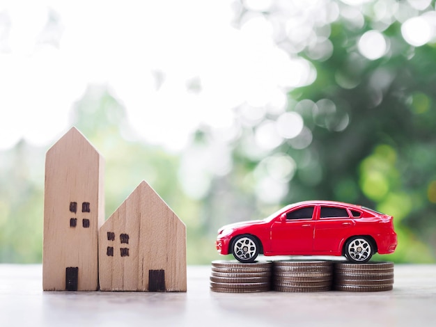 Miniature house and wooden toy car on stack of coins The concept of saving money for car and house