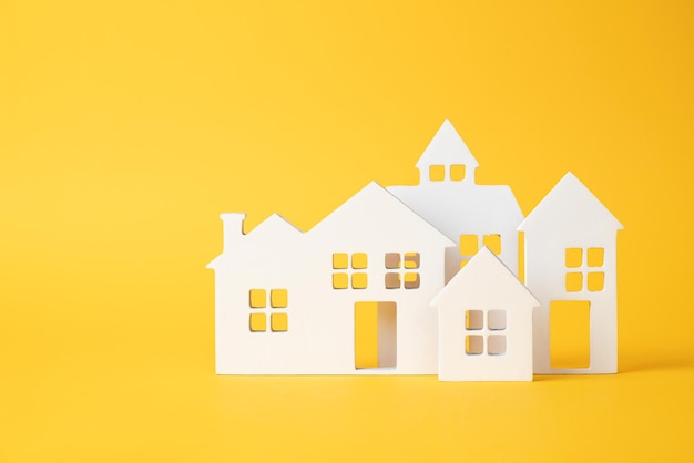 Miniature houses on yellow background Building blocks arranged in row