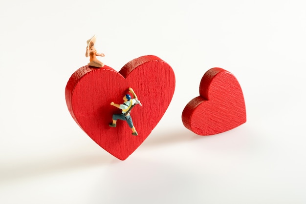 Miniature man climbing a red heart