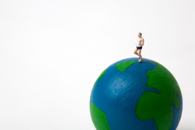 miniature man running on globe on white