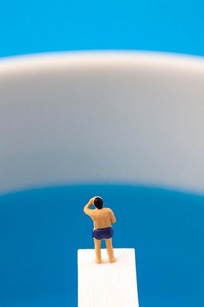 miniature man standing on diving board