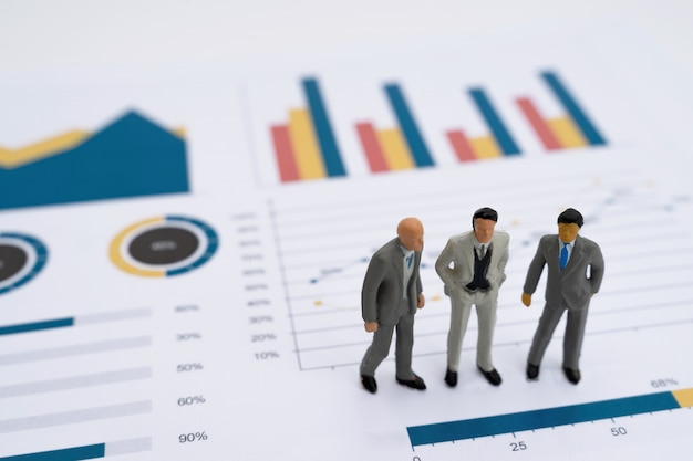 Miniature model of co-investment business people standing on business report graph