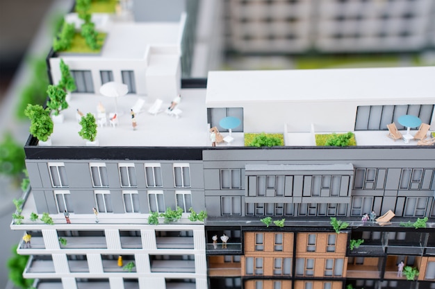 Миниатюрные модели, миниатюрные игрушечные здания, машины и люди. Городской макет. Новый строительный проект
