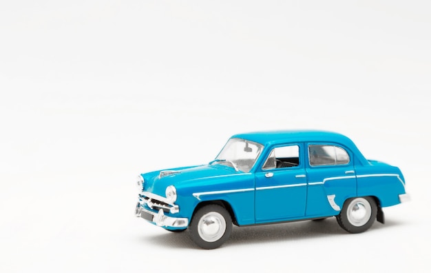 Miniature model of a toy blue retro car on a white background.