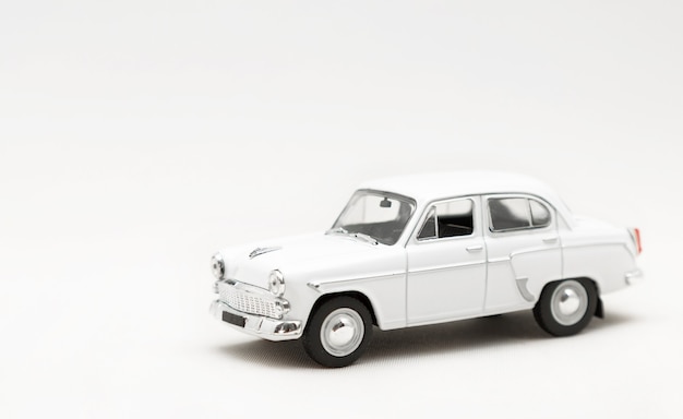 Miniature model of a toy white retro car on a white background.