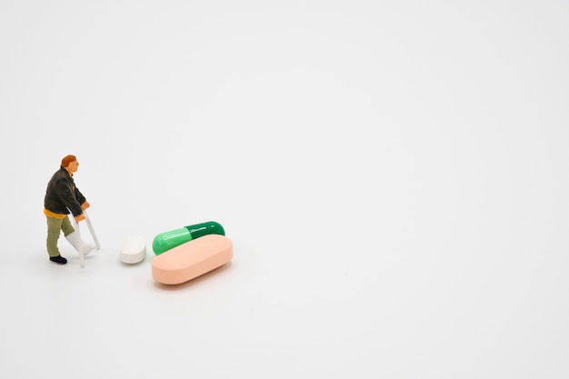 Miniature of old man broken legs model around with Pharmaceutical medicine pills