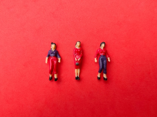 Miniature people are neatly arranged on a red background