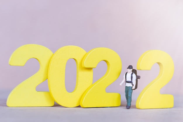 Miniature people backpacker standing on wooden number 2022 , Happy new year concept