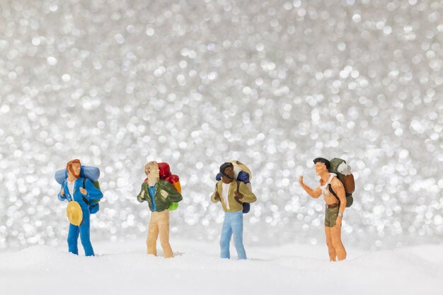 Miniature people, backpacker walking on snow
