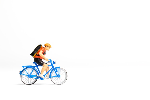 Persone in miniatura corriere in bicicletta con cassetta dei pacchi sul retro isolato su sfondo bianco, concetto di servizio di consegna espresso