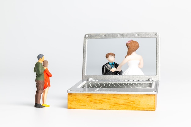 Miniature people Bride and groom virtual wedding on computer screen, Happy Valentines Day concept