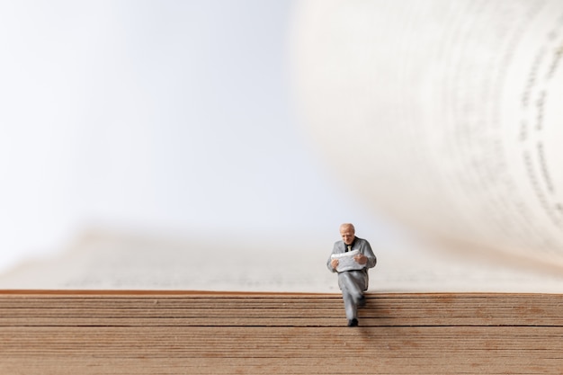 Miniature people: Businessman reading book on  old book 