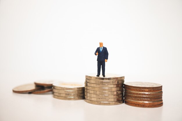 Miniature people, businessman show good job symbol on stack coins 