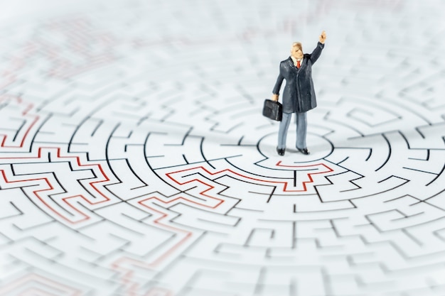 Miniature people Businessman standing on center of maze using 