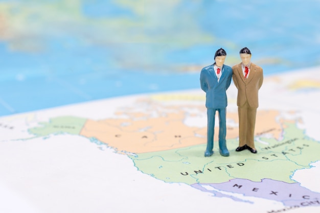 Miniature people, businessman standing on map American 