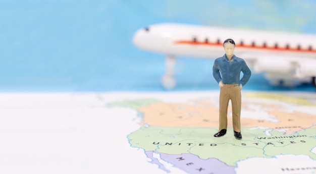 Miniature people, businessman standing on map American 