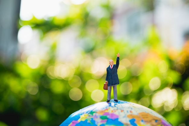 Miniature people, businessman standing on mini earth using as business and travel concept