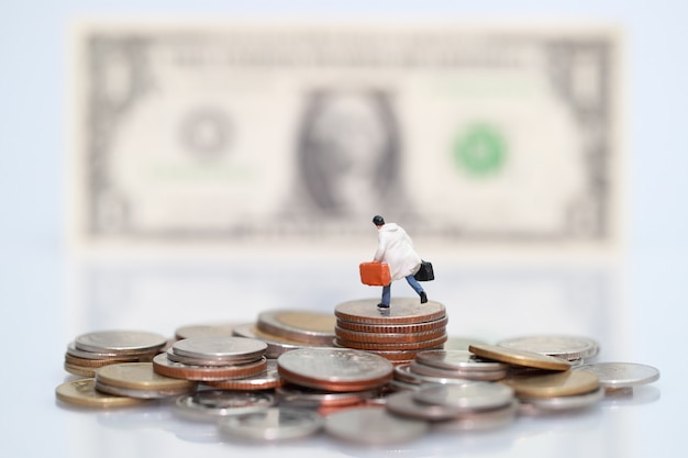 Photo miniature people: businessman standing on stacking coins