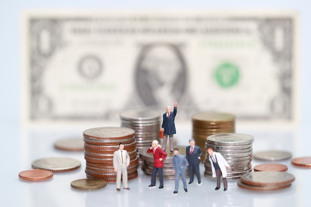 Miniature people: businessman standing on stacking coins 