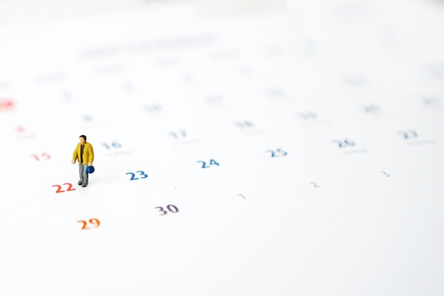Miniature people of businessman standing on white calendar Weekend time concept with copy space for