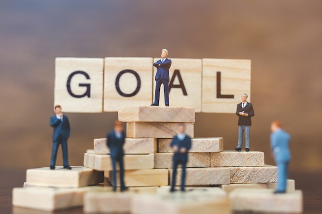 Miniature people: Businessman standing on wooden block