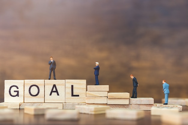 Miniature people: Businessman standing on wooden block