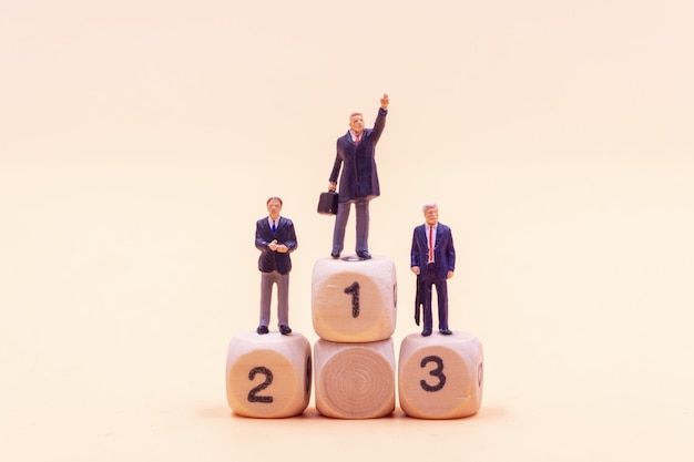 Miniature people Businessman standing on wooden podium