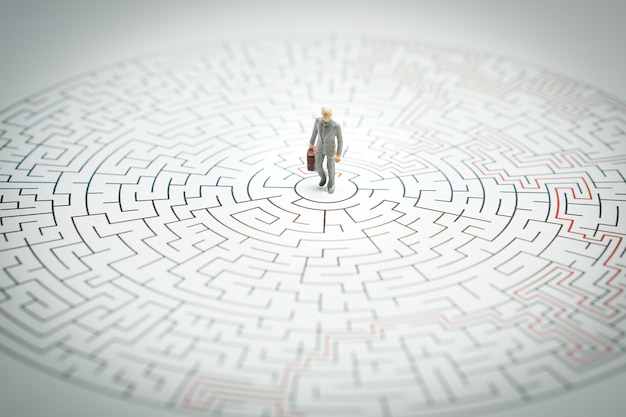 Miniature people Businessman Walking into a maze.