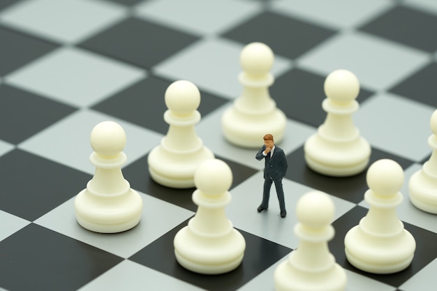 Miniature people businessmen standing on a chessboard with a chess 