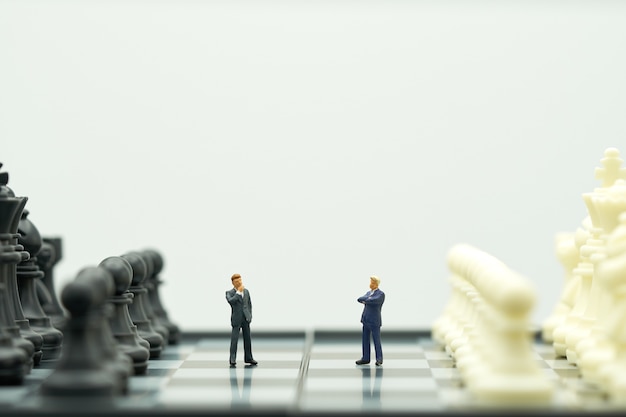 Miniature people businessmen standing on a chessboard with a chess 