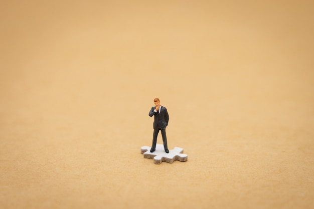 Miniature people businessmen standing on white Jigsaw. using as background 