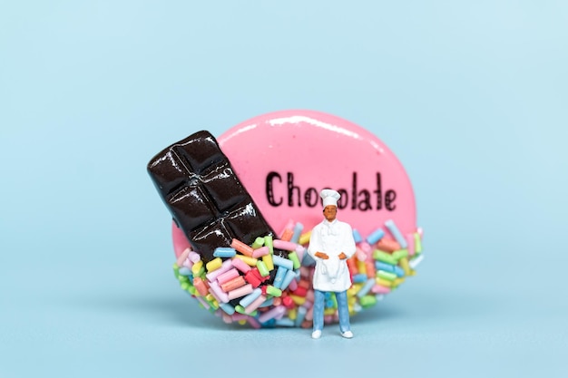 Miniature people Chef with chocolate cookie on a blue backgroundWorld Chocolate Day Concept