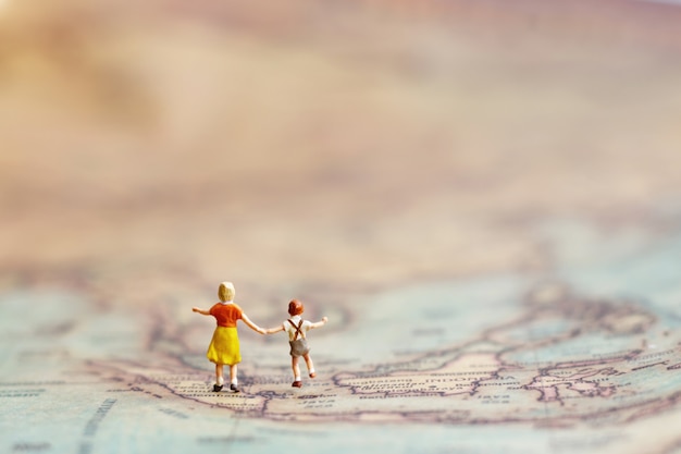 Miniature people, children with brother with globe walking to destination