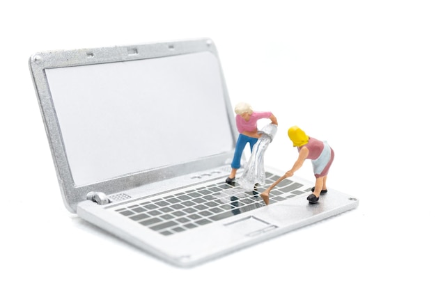 Persone in miniatura che puliscono il computer portatile su sfondo biancoxa