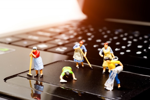 Miniature people cleaning notebook.