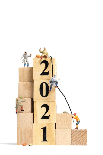 Miniature people: climb up on wooden cube with number 2021