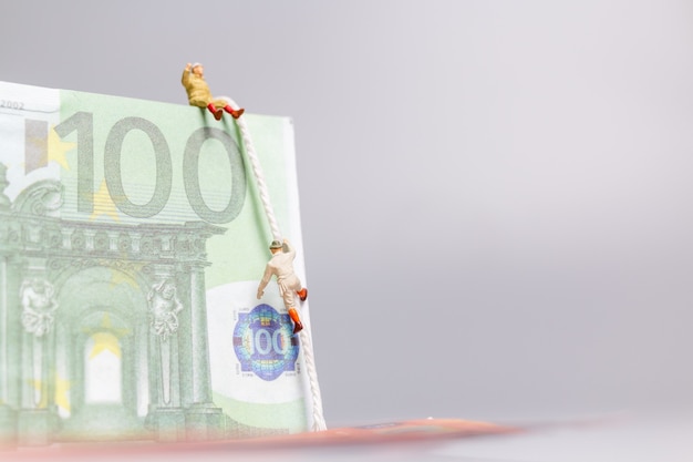 Persone in miniatura, scalatore si arrampica su un concetto di business delle banconote in euro.