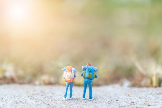 Miniature people concept with Travelers miniature with backpack standing on The road