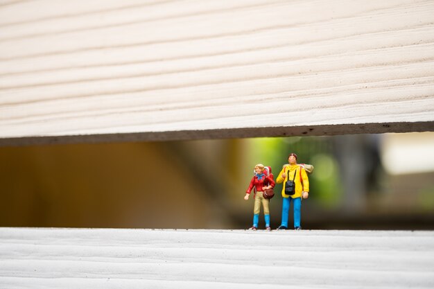 Miniature people, couple backpacker standing on white texture background, used for travel and holida