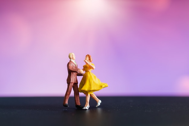 Gente in miniatura, coppia che balla con sfondo colorato