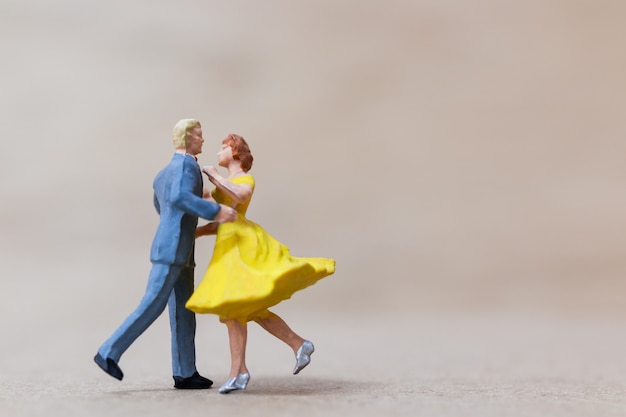Miniature people , Couple dancing on wooden  background