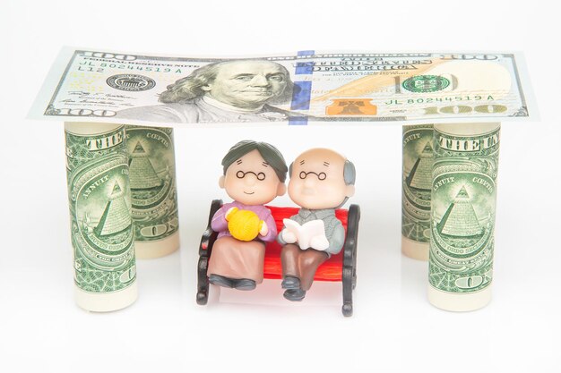 Miniature people a couple of pensioners under the house of dollars financial security and pension for the elderly concept of financial independence