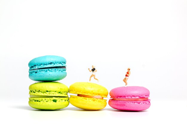 Miniature people , couple running on colourful french macaroon , 