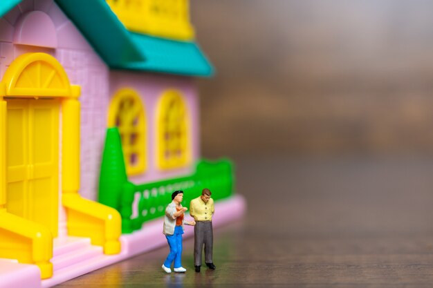 Miniature people , couple standing together in front of their house