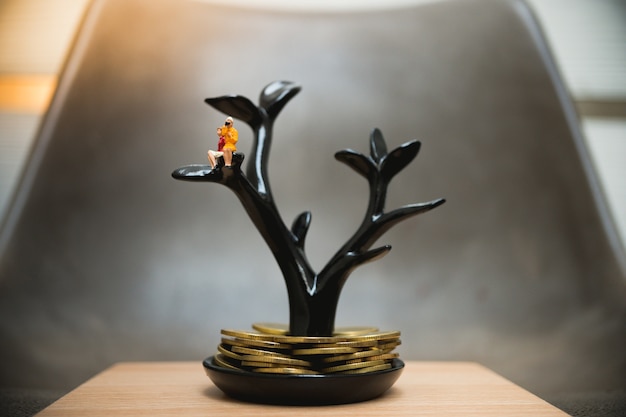 Miniature people, couple woman sitting on tree structure with stack coins used for business growing 