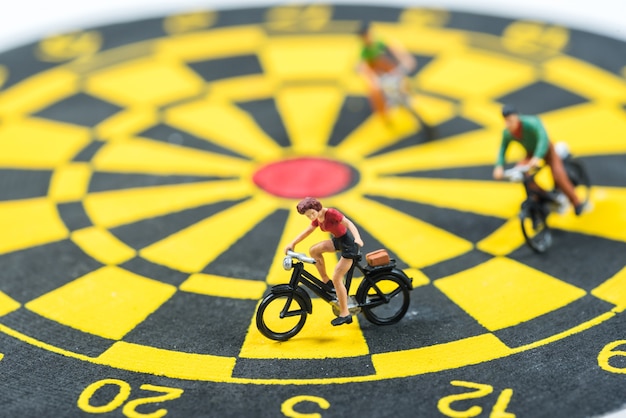 Miniature people cycling on dart board