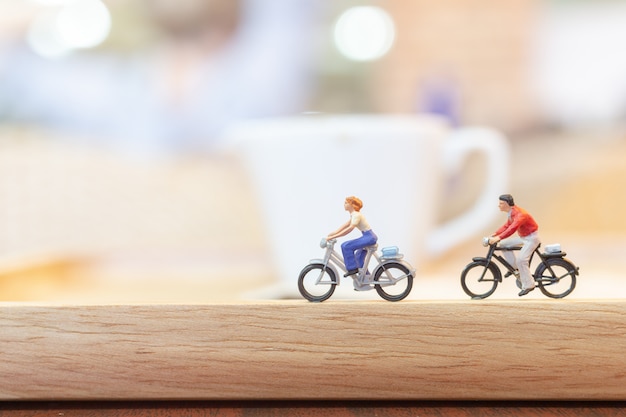 Miniature people  cycling on wooden bridge