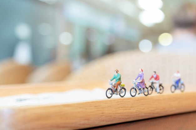 Miniature people  cycling on wooden bridge